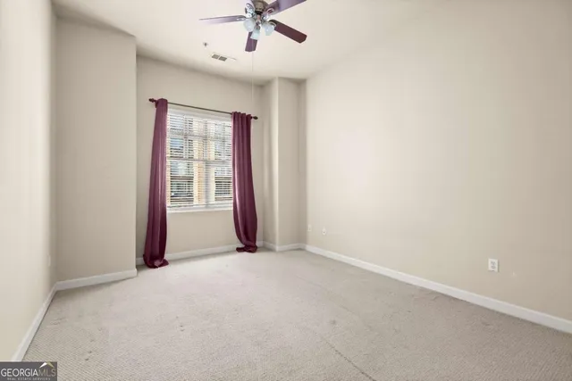 an empty room with a window and a ceiling fan
