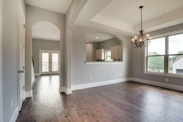 a view of a room with wooden floor chandelier and windows