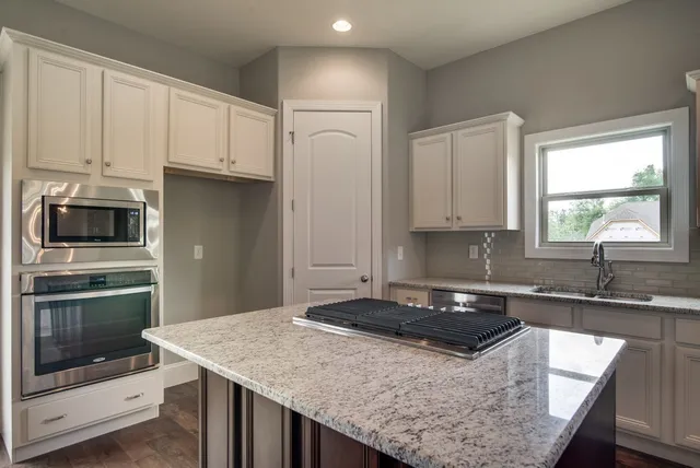 a kitchen with granite countertop a sink a stove and cabinets