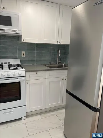 a kitchen with granite countertop white cabinets and white stove