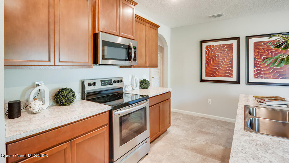 409 Old Road Palm Bay, FL 32908 - Photo 3 of 15 a kitchen with stainless steel appliances granite countertop a stove a sink and a microwave