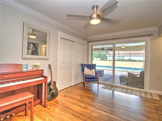 a living room with furniture a ceiling fan and a large window
