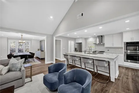 a living room with furniture kitchen view and a wooden floor