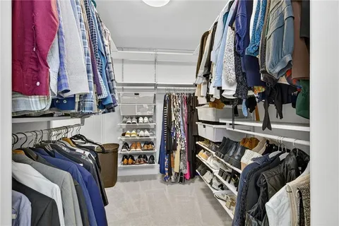 a view of walk in closet with clothes and shoes