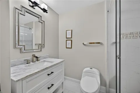 a bathroom with a granite countertop toilet sink mirror and vanity
