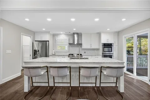 a kitchen with stainless steel appliances granite countertop a table chairs sink refrigerator and cabinets
