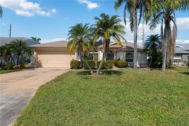 a view of a house with a yard and palm trees