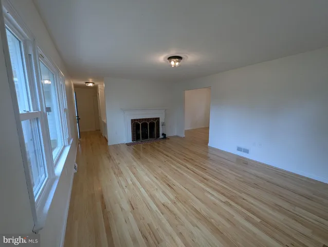 a view of empty room with wooden floor and fireplace
