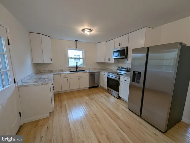 a kitchen with granite countertop a refrigerator stove top oven and sink