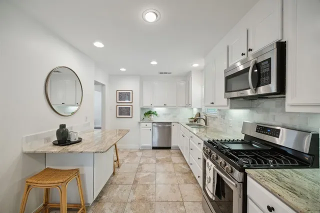 a kitchen with stainless steel appliances granite countertop a stove a sink and a microwave