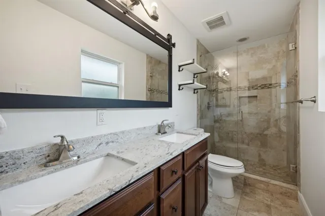 a bathroom with a granite countertop sink a toilet and a mirror