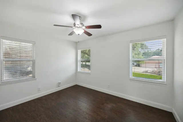 a view of an empty room with a window and a ceiling fan