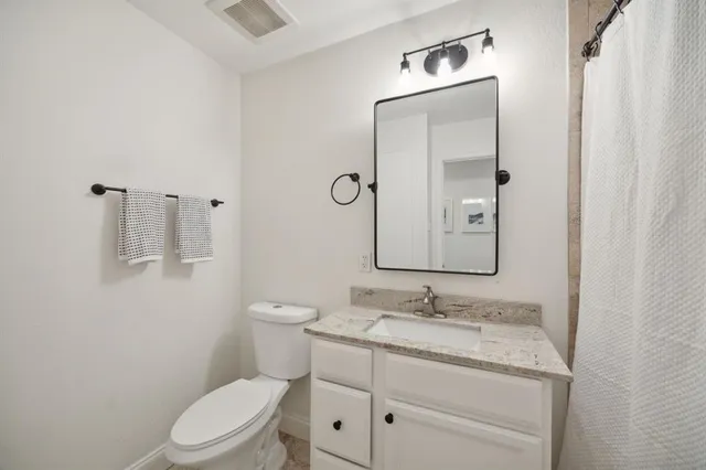 a bathroom with a granite countertop toilet a sink and a mirror