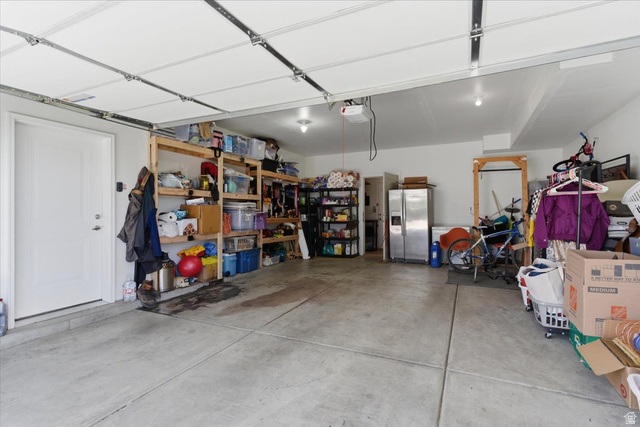370 West Knights Lane Layton, UT 84041 - Photo 30 of 31 Spacious garage with a concrete floor, built-in shelving, and a pedestrian door