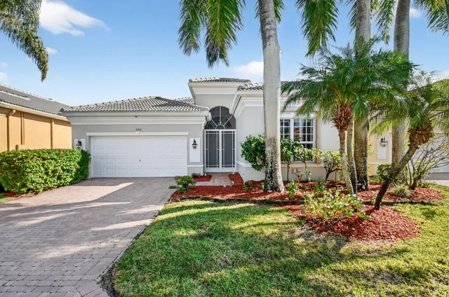 a view of a house with a yard and palm trees