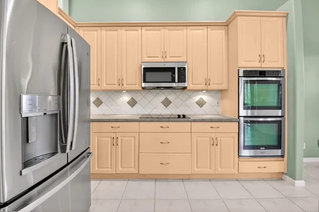 a view of a kitchen with stainless steel appliances granite countertop a stove top oven a refrigerator a sink and a table