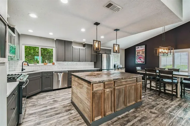 a kitchen with a stove a sink a kitchen island with chairs and wooden floor