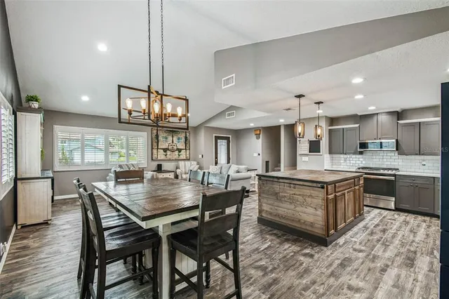 a kitchen with stainless steel appliances granite countertop a table chairs sink and cabinets