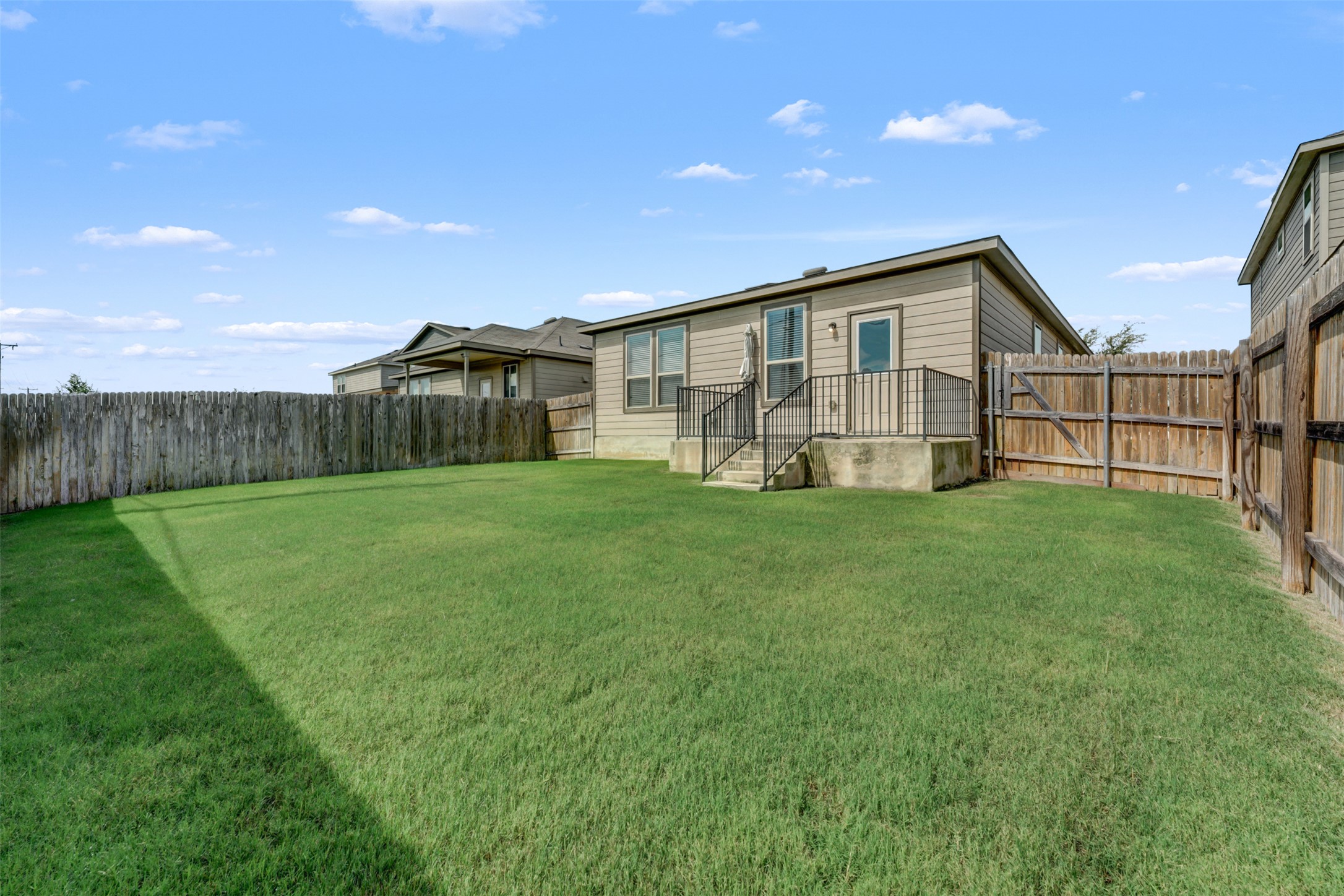 213 Ibis Falls Loop Jarrell, TX 76537 - Photo 31 of 37 A verdant backyard offers a private, spacious area for outdoor activities, enclosed by a sturdy wooden fence.