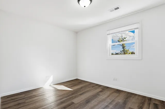 an empty room with wooden floor and window