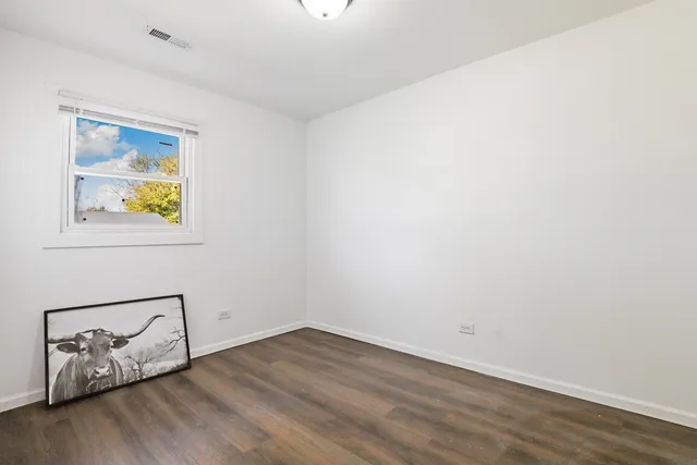 an empty room with wooden floor and painting on the wall