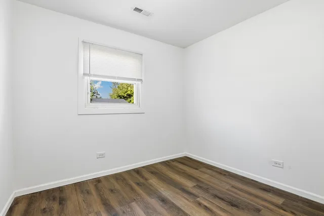 an empty room with wooden floor and window