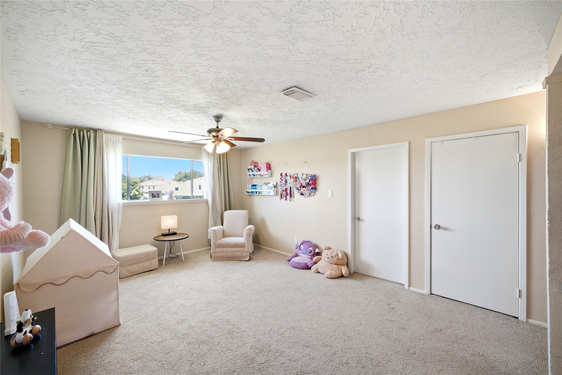4718 Temple Bell Drive Spring, TX 77388 - Photo 29 of 50 A bright and spacious kids' room with a large window, plush carpet, and neutral walls. It features a ceiling fan, cozy seating, and playful decor, creating a welcoming and comfortable space.