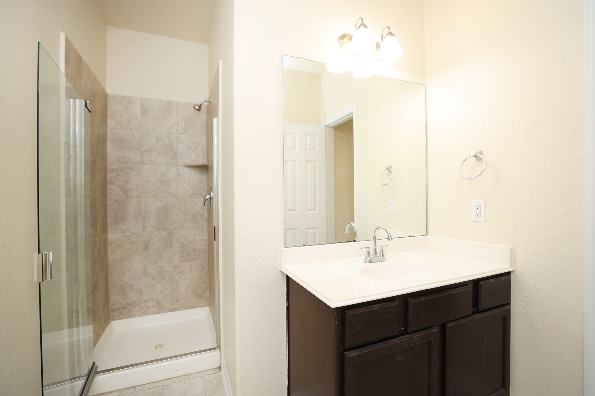 18402 Spruce Tree Line Trail Houston, TX 77084 - Photo 12 of 30 This bathroom features a modern glass-enclosed shower with tile accents and a spacious vanity with a large mirror, offering a clean and bright space.