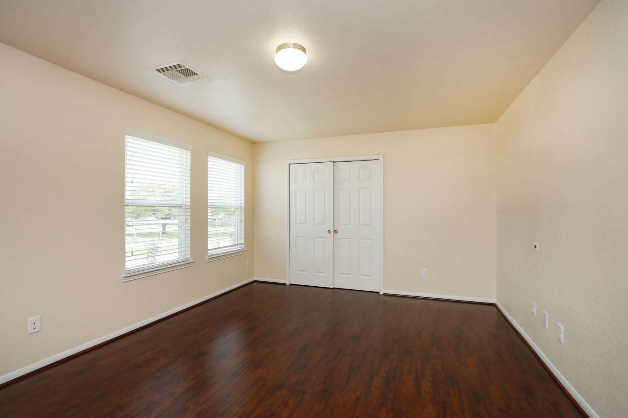 18402 Spruce Tree Line Trail Houston, TX 77084 - Photo 13 of 30 Bright, spacious room with hardwood floors, neutral walls, and ample natural light from two large windows. Features a double-door closet and a ceiling light.