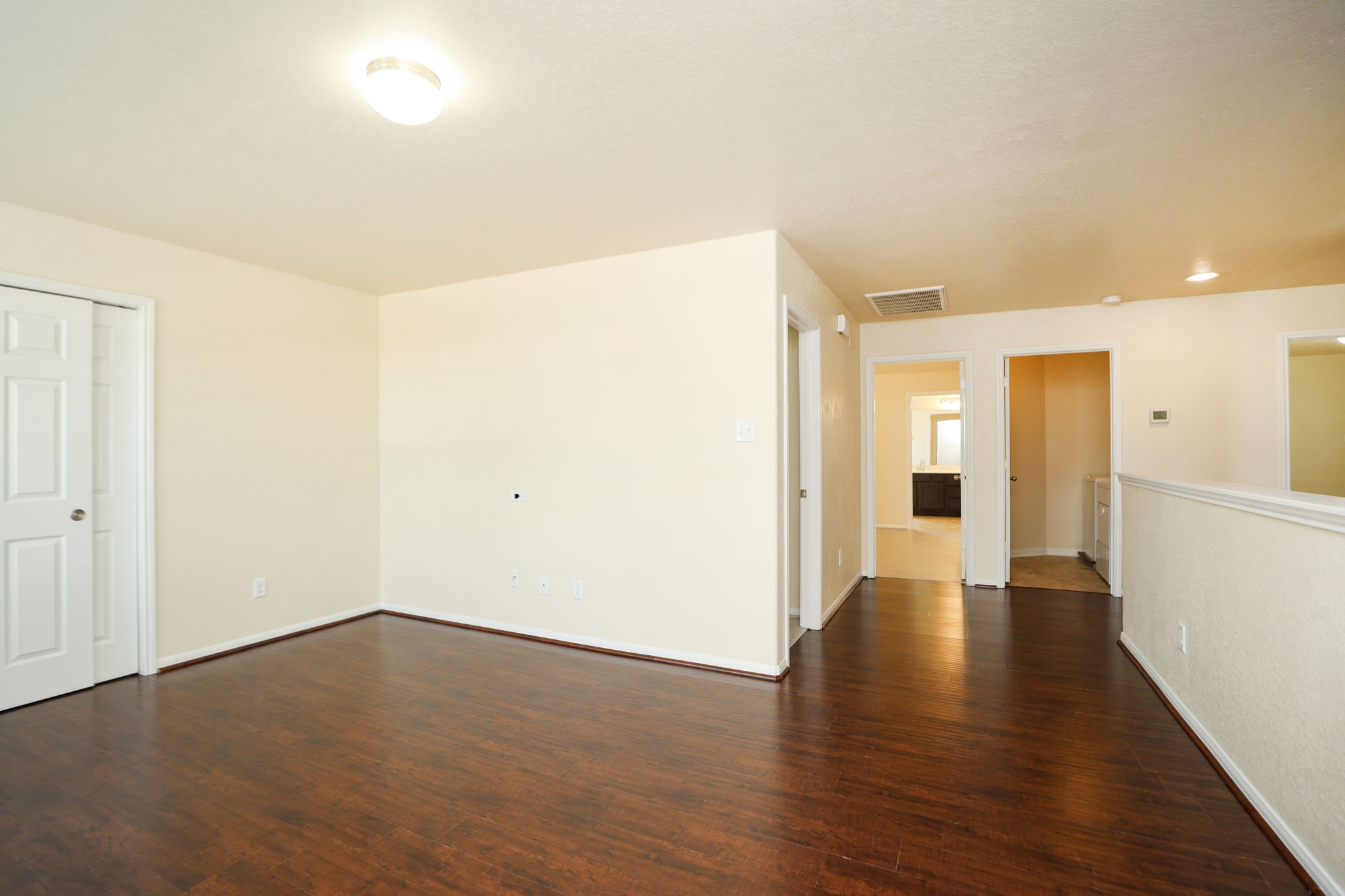 18402 Spruce Tree Line Trail Houston, TX 77084 - Photo 14 of 30 This photo showcases a bright hallway with hardwood flooring, light-colored walls, and multiple doorways leading to other rooms. The space is well-lit with recessed lighting and a ceiling fixture, creating a welcoming atmosphere.