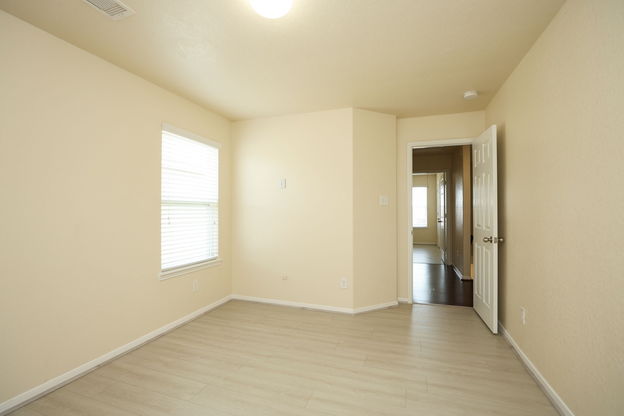18402 Spruce Tree Line Trail Houston, TX 77084 - Photo 21 of 30 Bright room with light-color walls and laminate flooring. It features a window with blinds, providing natural light, and an open door leading to a hallway. Ideal for a bedroom or office space.