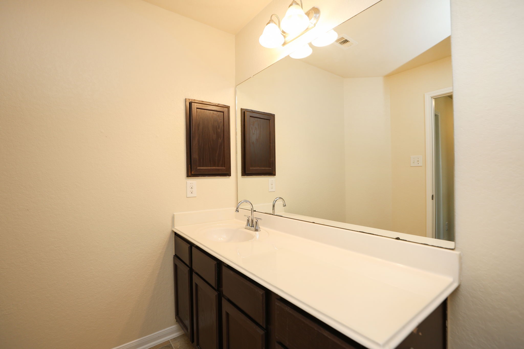 18402 Spruce Tree Line Trail Houston, TX 77084 - Photo 23 of 30 This is a bathroom with a single sink vanity featuring dark wood cabinets and a large mirror. The neutral walls and overhead lighting create a bright and clean atmosphere.