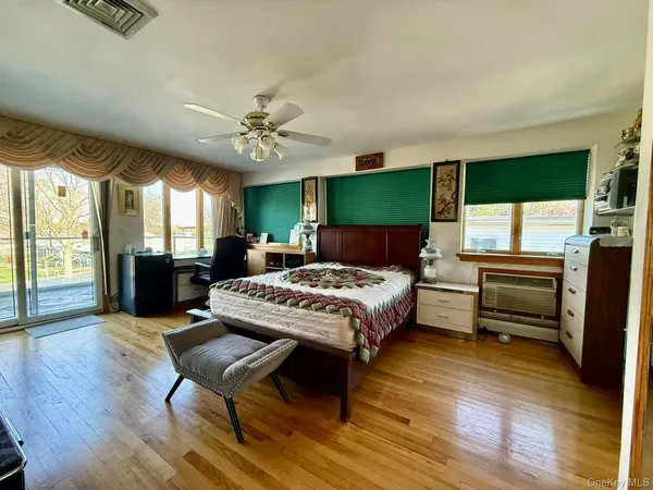 a spacious bedroom with a bed a bookshelf a desk and chair with wooden floor