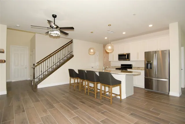 a kitchen with stainless steel appliances kitchen island granite countertop a refrigerator a stove a microwave oven a sink with island and chairs