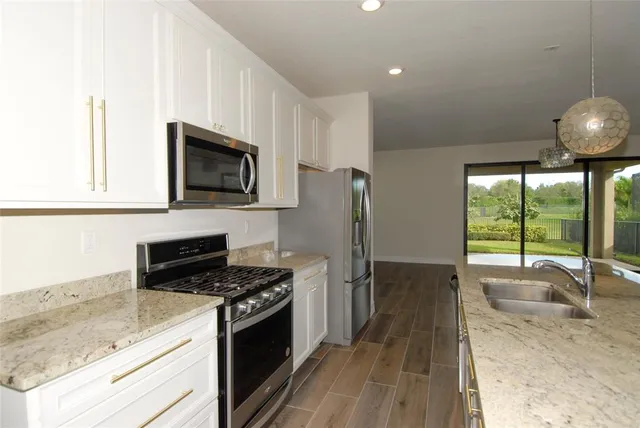 a kitchen with stainless steel appliances granite countertop a stove a sink and a microwave