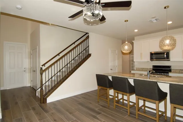 a dining room with wooden floor a chandelier a wooden table and chairs