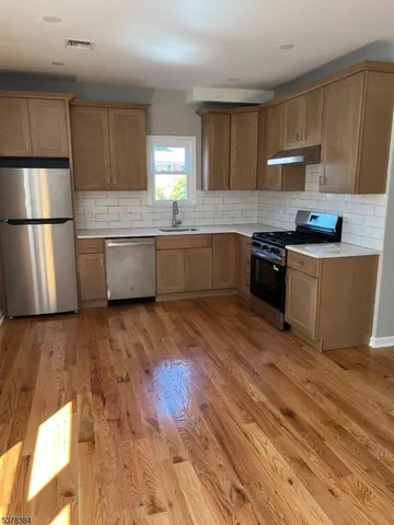 a kitchen with stainless steel appliances wooden floors and wooden cabinets