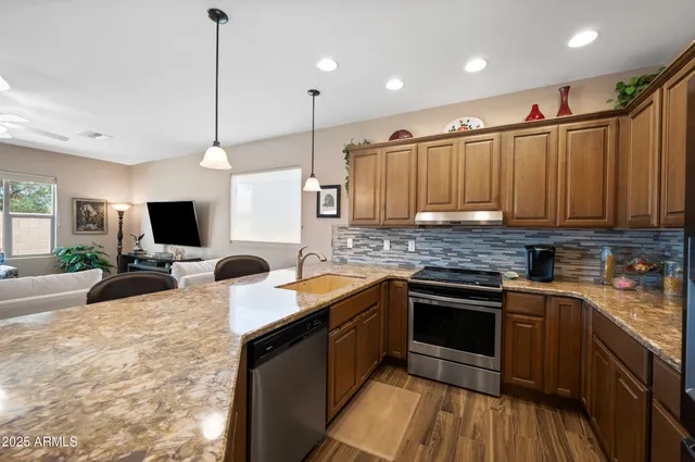 a kitchen with stainless steel appliances granite countertop wooden cabinets a sink dishwasher a stove and a refrigerator