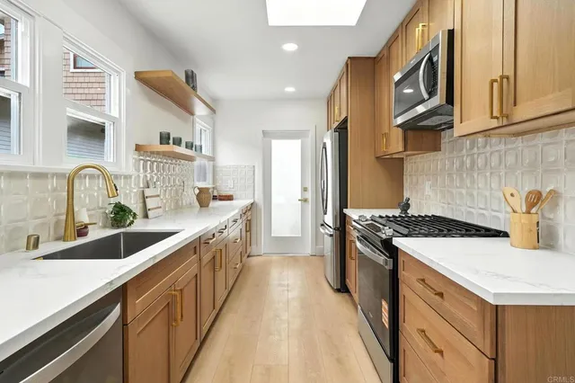 a kitchen with stainless steel appliances granite countertop a sink a stove and a refrigerator