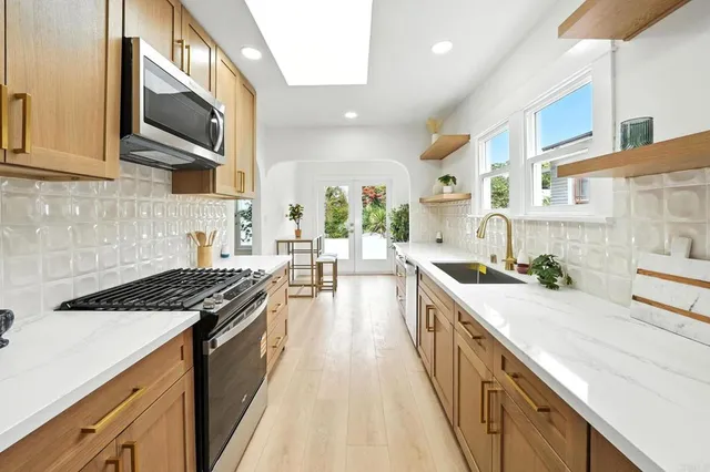 a kitchen with stainless steel appliances a stove top oven a sink a counter space and cabinets