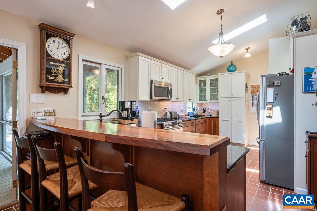 2110 Whippoorwill Road Charlottesville, VA 22901 - Photo 5 of 37 a kitchen with stainless steel appliances granite countertop a refrigerator a sink dishwasher a stove and a dining table with wooden floor
