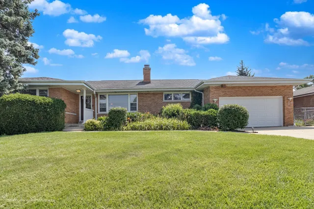 a view of a white house next to a yard with plants and trees