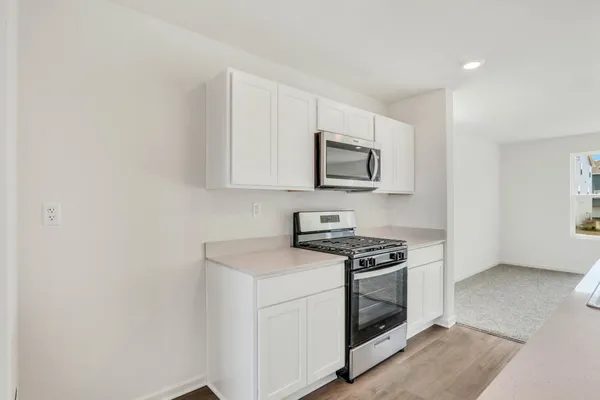 a kitchen with granite countertop a sink and a stove with wooden floor