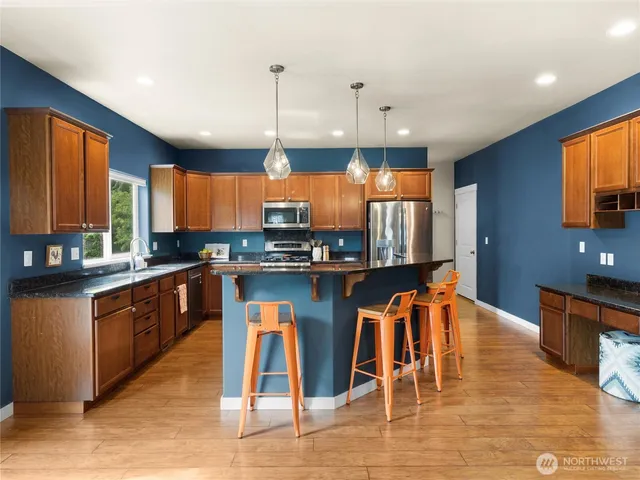 a kitchen with stainless steel appliances granite countertop a stove top oven a sink dishwasher and a refrigerator