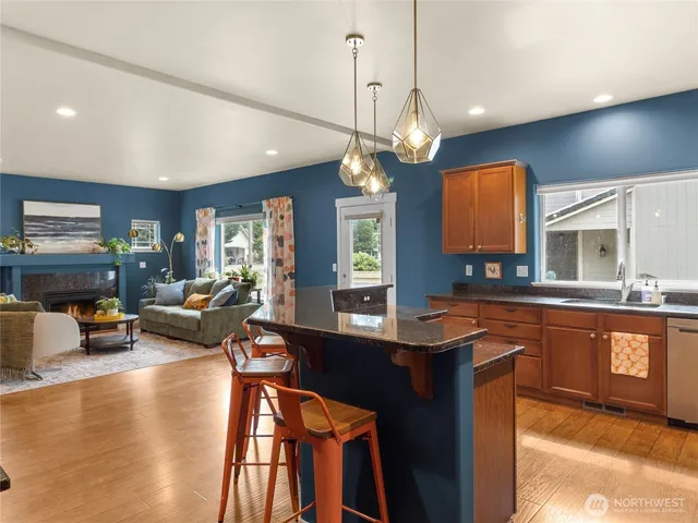 a kitchen with stainless steel appliances granite countertop a stove a sink dishwasher a couches chairs and couches with wooden floor