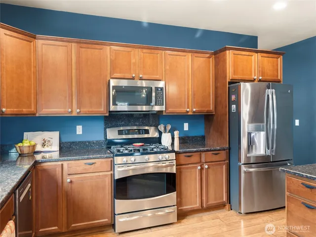a kitchen with stainless steel appliances granite countertop a refrigerator stove and microwave