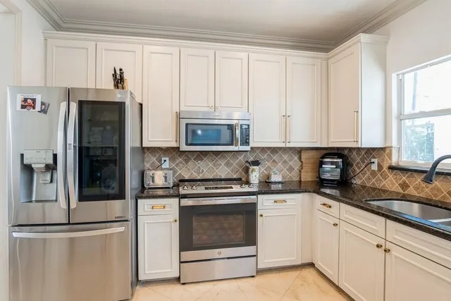 a kitchen with white cabinets and stainless steel appliances