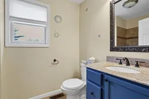 a bathroom with a granite countertop toilet a sink and mirror