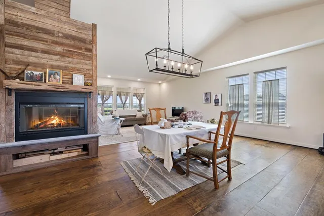 a dining room with wooden floor a chandelier a wooden table and chairs