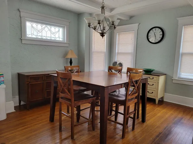 a view of a dining room with furniture a chandelier and wooden floor